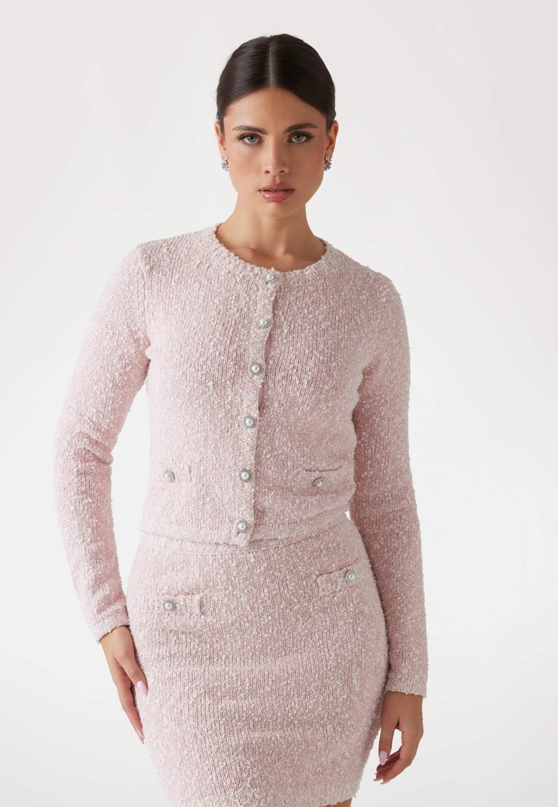 Pink tweed cardigan with long sleeves, round neckline, and decorative buttons. Features two pockets with similar button accents.