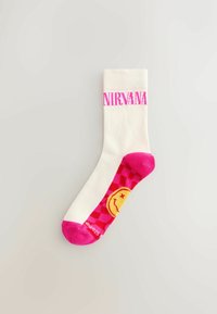 Weißer Crew-Socken mit pinkem "NIRVANA"-Logo, das ein lachendes Gesicht und ein Schachbrettmuster in Pink und Gelb auf dem Fuß zeigt.