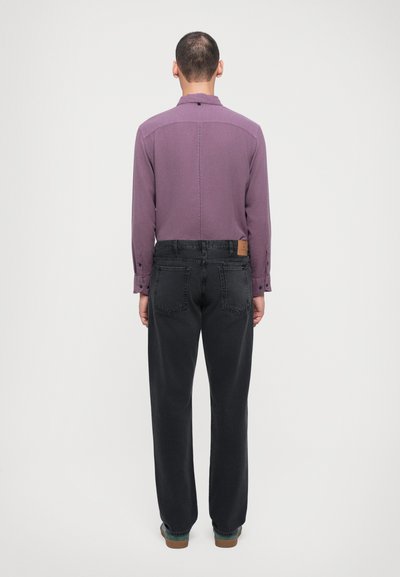 Paars overhemd met lange mouwen, een kraag en knoopsluiting, gecombineerd met losse zwarte jeans met achterzakken en een bruin leren label.