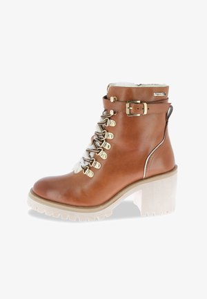 Botín de cuero marrón hasta el tobillo con suela de grano blanca, tacón grueso, ojales dorados, parte delantera con cordones, correa con hebilla y forro de piel de lana blanca.