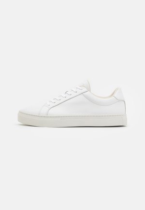 Hvite lær sneakers med avrundet tå, flat hvit såle og minimale sømdetaljer på sidene. Snøring og mykt indre fôr er til stede.
