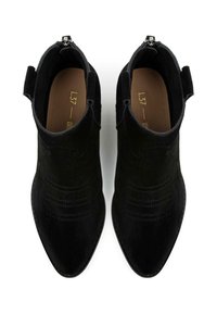 Botine negre din suede, cu vârful ascuțit, detalii cusute și închidere cu fermoar la spate. Textură netedă și design minimalist.