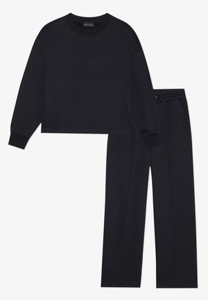 Black cotton loungewear set featuring a relaxed-fit long-sleeve top and straight-leg pants with an elastic waistband. Simple design, no patterns.