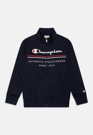 Sweat-shirt zippé bleu marine avec logo Champion, rayures rouges et blanches, poches avant et texte « Authentic Athleticwear Since 1919 » sur la poitrine.