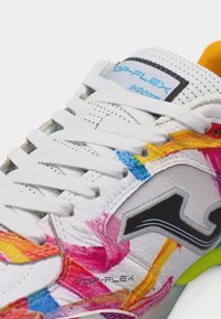 Κοντινό πλάνο λευκού αθλητικού παπουτσιού με πολύχρωμες πινελιές από χρώμα, λευκά κορδόνια, μαύρο λογότυπο και κείμενο "TOP-FLEX" στο πλάι και στη γλώσσα.