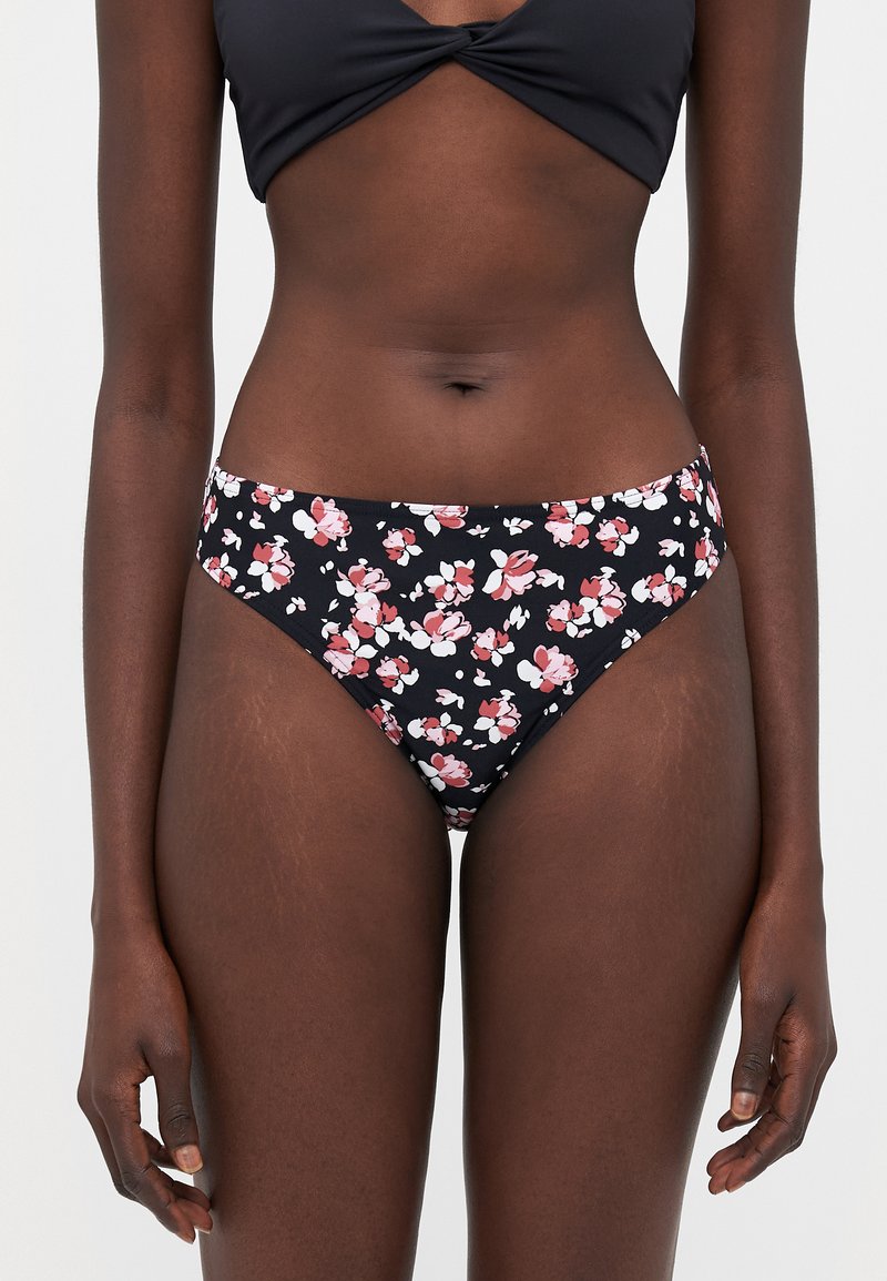 Blomsterbikini-bunn med svart bakgrunn og rosa og hvite blomster. Laget av mykt stoff, har den en lav midje og glatt tekstur.