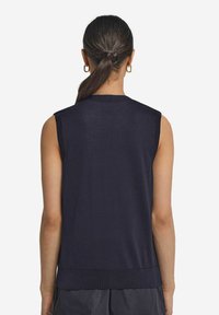 Mörkblå ärmlös stickad topp med rund halsringning, ribbad fåll och slät textur. Enkelt design utan synliga knäppningar eller dekorationer.