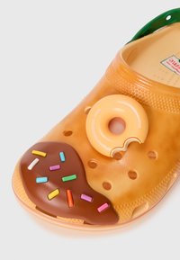 Oranger Gummischuh mit Schokoladenglasur und bunten Streuseln. Besitzt einen dekorativen Donut an der Vorderseite.