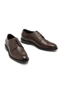 O pereche de pantofi de dress din piele maron închis, lustruți, cu șireturi, pe un fundal alb, poziționați astfel încât un pantof să fie ușor mai în față decât celălalt.