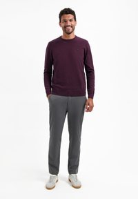 Bordeaux gebreide trui met ronde hals, gecombineerd met lichtgrijze op maat gemaakte broek en witte sneakers, met een gestructureerde stof en een aansluitende pasvorm.