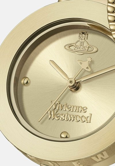 Montre-bracelet en métal doré avec un cadran circulaire, présentant une finition texturée, des aiguilles dorées et la marque "Vivienne Westwood" embossée sur le cadran.