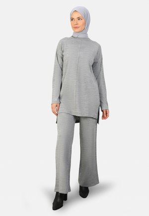 Gray tunic and pant set made of soft, textured fabric. Tunic features side slits; paired with flared pants and black ankle boots.