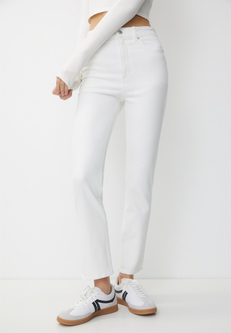 White high-waisted jeans made of denim, featuring a fitted silhouette, straight leg, four pockets, and a button-fly closure.