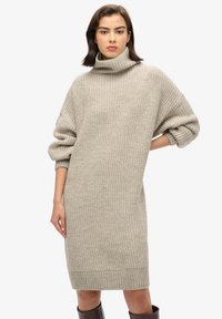 Vestido de cuello alto de punto en gris claro, con mangas holgadas y dobladillo acanalado. La textura de la tela parece suave con un patrón grueso.