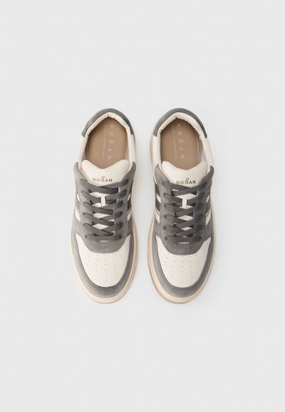 Sneakers z szarym zamszowym wierzchem, białym skórzanym czubkiem i beżową podeszwą, z sznurowadłami oraz perforowanymi detalami na czubku.