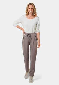 Grijze sweatpants met zijritszakken en een elastische tailleband, gecombineerd met een witte top met lange mouwen en lichte sneakers.