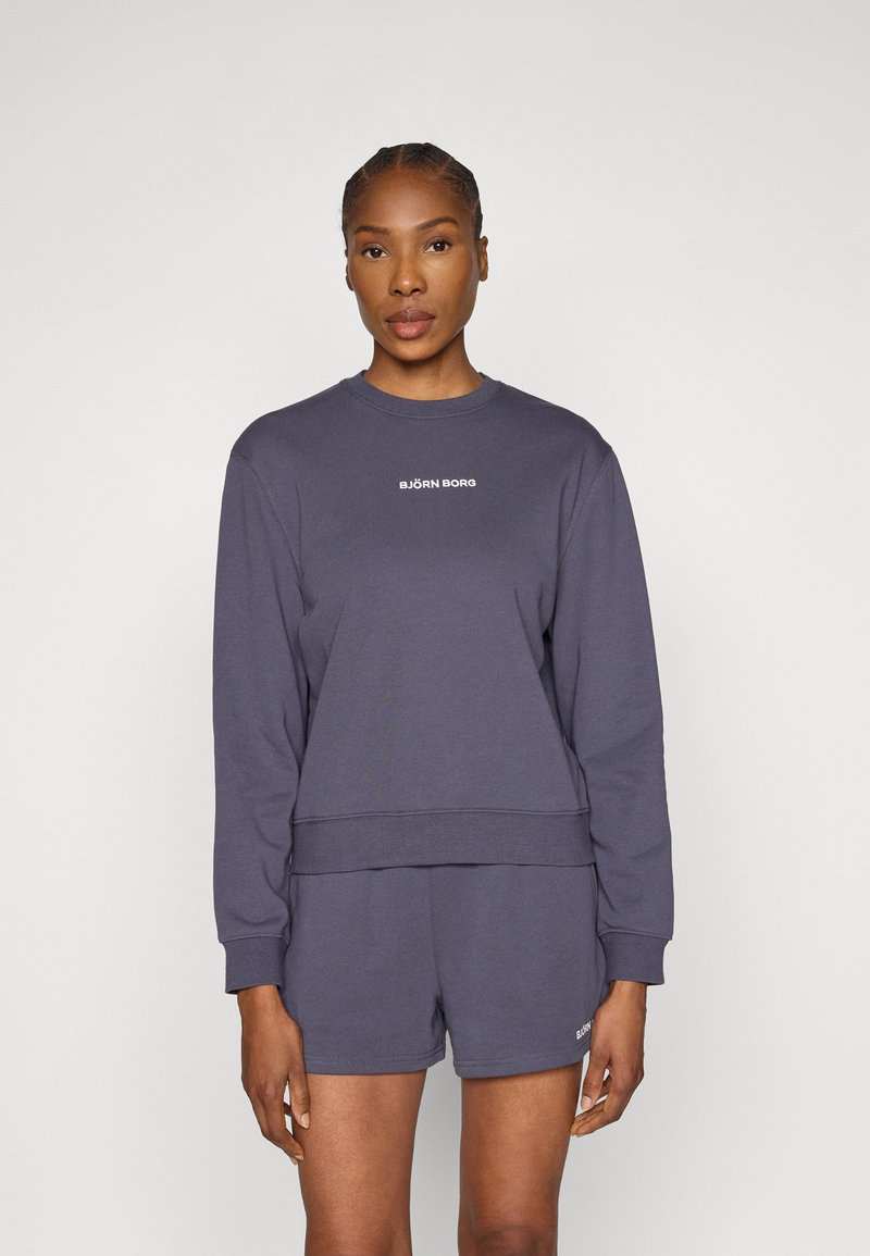 Γκρι φούτερ με μακριά μανίκια, ριμπ μανσέτες και ίσια ίσια τελείωμα. Διαθέτει λευκό λογότυπο στο στήθος. Συνδυάζεται με αντίστοιχα σορτς.