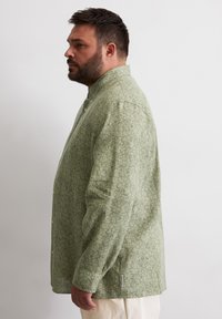 Grünes Langarmhemd aus strukturiertem Stoff mit floralem Muster, mit einemButton-down-Kragen und geradem Saum.