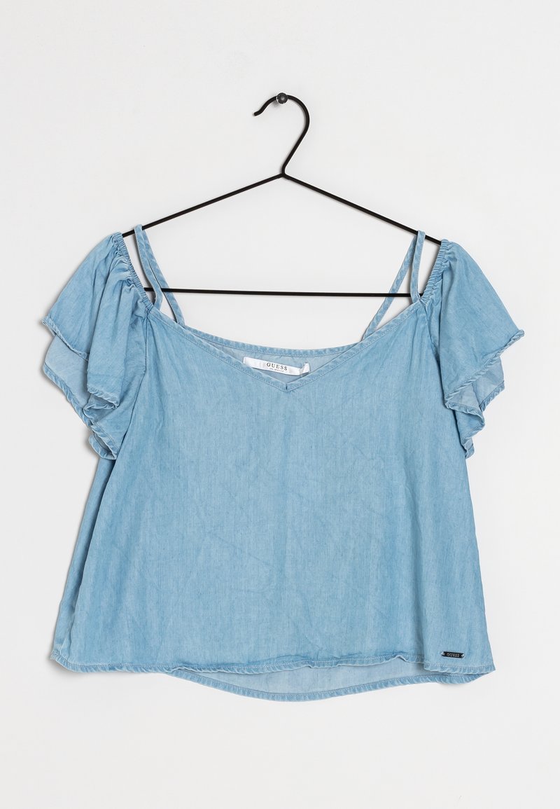 Blusa a maniche corte blu chiaro in tessuto denim, con scollatura a V, maniche svasate e orlo dritto. Etichetta nera in basso a sinistra.