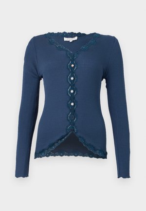 Gilet en maille côtelée marine à manches longues, avec une finition en dentelle le long de l'encolure et de la patte de boutonnage, et un ourlet festonné.