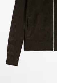 Ciemnobr�ązowa kurtka z teksturowanymi rękawami z dzianiny i gładką częścią główną, z suwakiem oraz bocznymi kieszeniami. Prążkowane wykończenia u dołu i na mankietach.