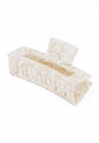 Translucent marmormönstrad hårklämma i krämfärg. Har en böjd design med vertikala utskärningar för säker grepp och stilflexibilitet.