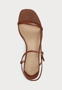 Kohvase nahast sandaal ruudukujulise varbaga, õhukeste rihmade ja pahkluu sidumisega. Siseosa on kaetud sujuva beeži voodriga ja embosseeritud brändinimega.