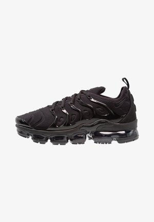 Sapatos de desporto pretos com um upper de tecido texturizado, detalhes brilhantes e uma sola proeminente com almofada de ar. Apresenta elementos de design distintos em forma de ondas.