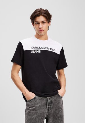 Juoda ir balta trumpomis rankovėmis medvilninė marškinėlių, ant krūtinės su ryškiai išspausdintu "KARL LAGERFELD JEANS" užrašu. Standartinio kirpimo.