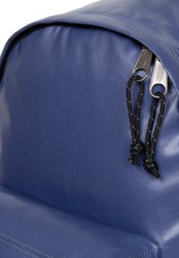 Niebieski plecak z tkaniny z zaokrąglonym wierzchem, zamkiem błyskawicznym, czarnymi sznurkami oraz teksturowaną powierzchnią zapewniającą trwałość.