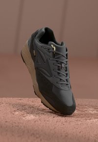 Gray sneaker with suede and mesh materials, featuring laces, perforations, and a rubber sole with a tan accent. Notable for its rugged design.