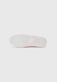 White sneaker outsole with zigzag tread pattern, featuring a solid rubber heel and a textured surface for grip and durability.