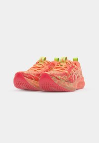 Baskets de sport roses vives avec un dessus en tissu texturé, des accents néon et une semelle à motifs avec des découpes pour l'adhérence et la flexibilité.