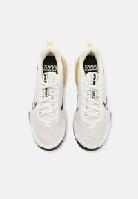 Baltas mežģīņu sporta apavi ar melniem akcentiem, apaļa purngala forma, plakani auklas un brūna zole, uz kuras ir "Air Max" zīmols melnāiekšē. 