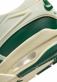 Sneaker con tomaia color crema con accenti verdi, finitura testurizzata, ammortizzazione ad aria visibile e un distintivo logo swoosh.