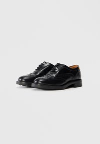 Black leather brogue shoes with perforated detailing, rounded toe, and lace-up closure. Durable rubber sole. Classic design with subtle accents.