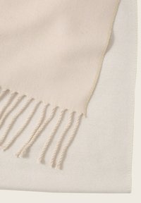 Lichtbeige sjaal met franjes, gemaakt van zachte stof. Gladde textuur met een eenvoudig, minimalistisch ontwerp en subtiele stikdetails.