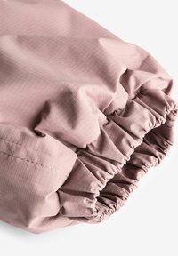 Rosa texturerad tyg med en samlad elastisk manschett, som har ett subtilt rutmönster och en slät yta, vilket ger ett mjukt och flexibelt utseende.