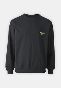 Felpa nera a maniche lunghe con collo rotondo, polsini e orlo a costine, piccolo logo giallo "JACK & JONES" sul lato sinistro del petto.