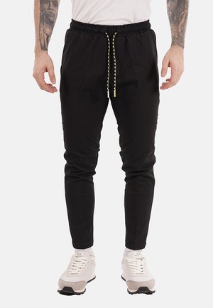 Pantaloni jogger neri in cotone con vita elasticizzata e dettaglio con coulisse, caratterizzati da gambe affusolate e tasche laterali.