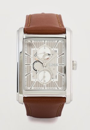 Rechthoekig zilveren horloge met witte skeletwijzerplaat, twee kleine subwijzerplaten, "BOSS"-logo en bruin lederen band met stiksels.