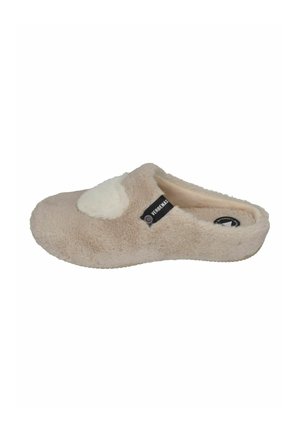 Furry beige slipper with a soft, white accent on the top. It has a low-profile design and textured sole for grip. Brand label visible.