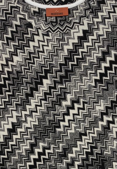 Svart, vitt och grått zigzag-mönster på tyg med en brun etikett som står "MISSONI" nära toppen i mitten.