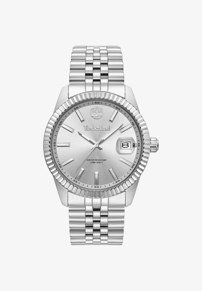 Zilveren roestvrijstalen horloge met een gestructureerde wijzerplaat, luminescerende uurmarkeringen, datumscherm en een geribde bezel. Waterbestendig tot 50 meter.