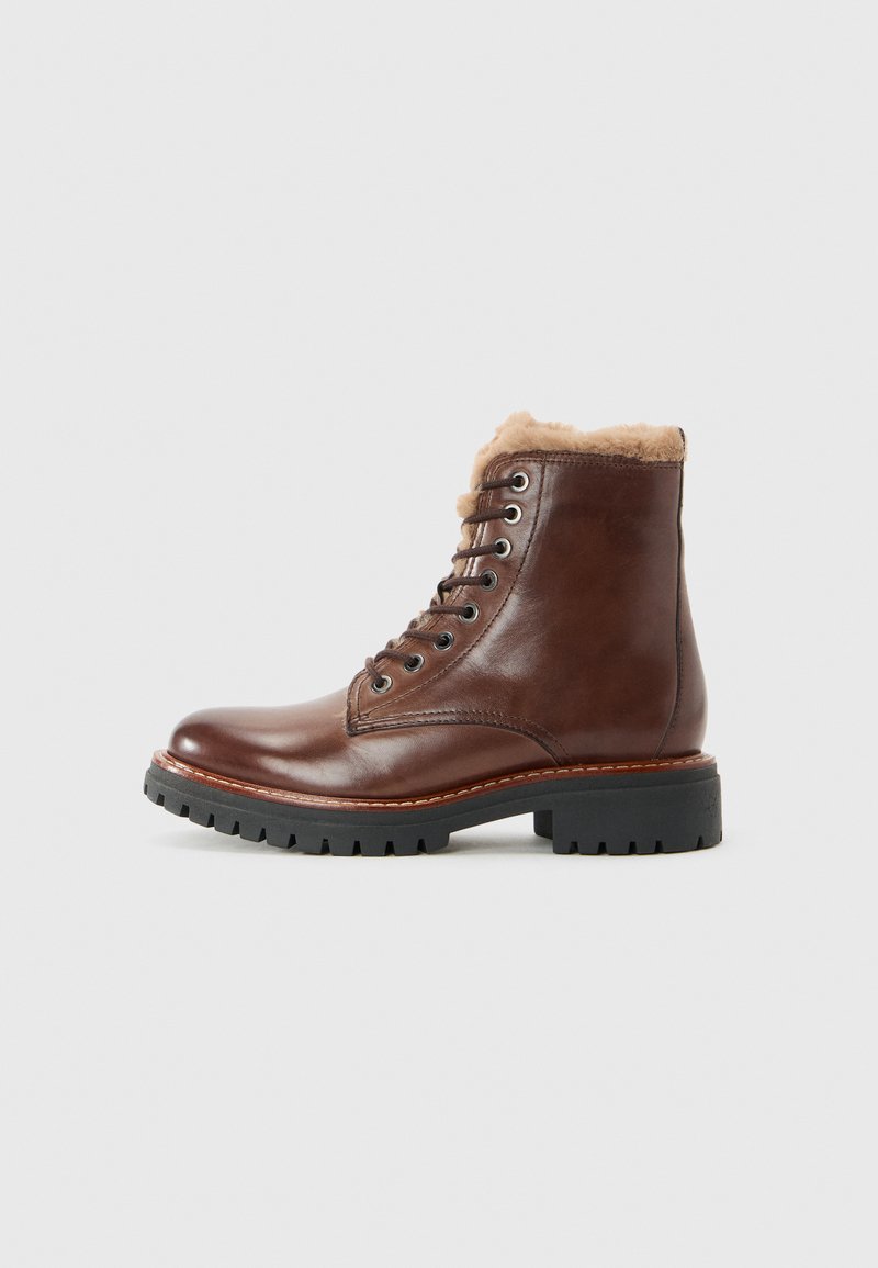 Botte d'hiver en cuir brun à lacets avec doublure en shearling et semelle en caoutchouc noir épais, présentée en profil latéral sur fond blanc.