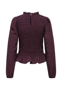 Violet spalvos ilgomis rankovėmis bliuska su susiraukšlėjusia tekstūra, volantais apatinėje dalyje ir rakto skylutės detalėmis nugaros pusėje. Pagaminta iš lengvos medžiagos su raukšlėtu apdaila.