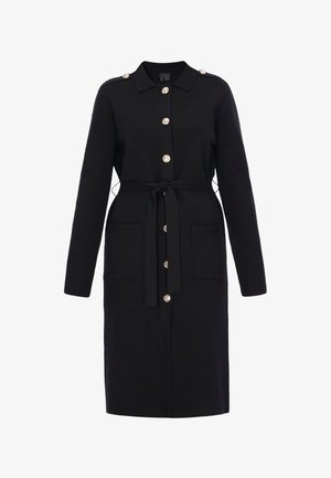 Lang sort frakke med knapper foran, to store lommer, skulderstropper og bælte i taljen.