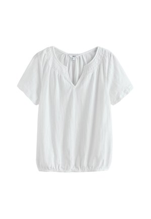 Blouse blanche à manches courtes avec un col en V, un ourlet élastique et des détails délicats en dentelle autour du col.