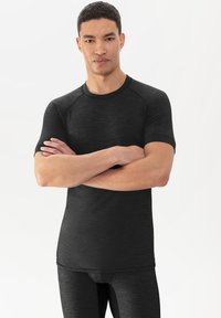 Zwart sportshirt met een ronde halslijn, korte raglanmouwen en een aansluitend ontwerp. Gemaakt van een gestructureerd, vochtafvoerend materiaal.