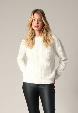Pull en tricot côtelé blanc avec des manches longues, un col rond et une texture douce ; associé à un pantalon noir ajusté. Design minimaliste.